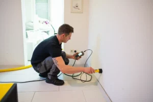 Techniker sucht nach dem Leck in der Wand mittels Leckageortung