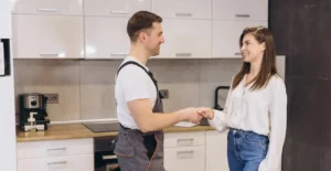 Klempner und Frau schütteln sich in der Küche die Hände